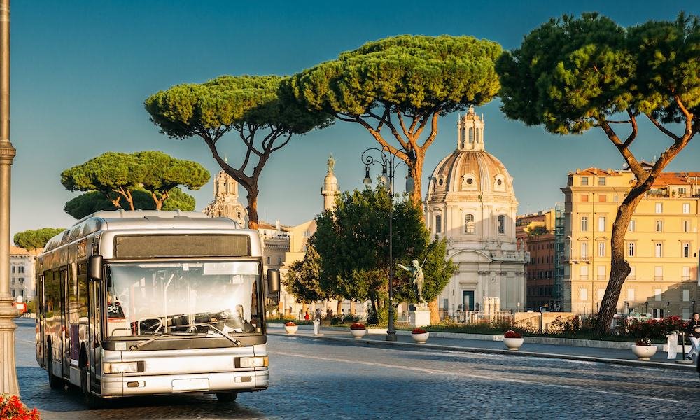 A city bus passing the pine trees and churches of central Rome