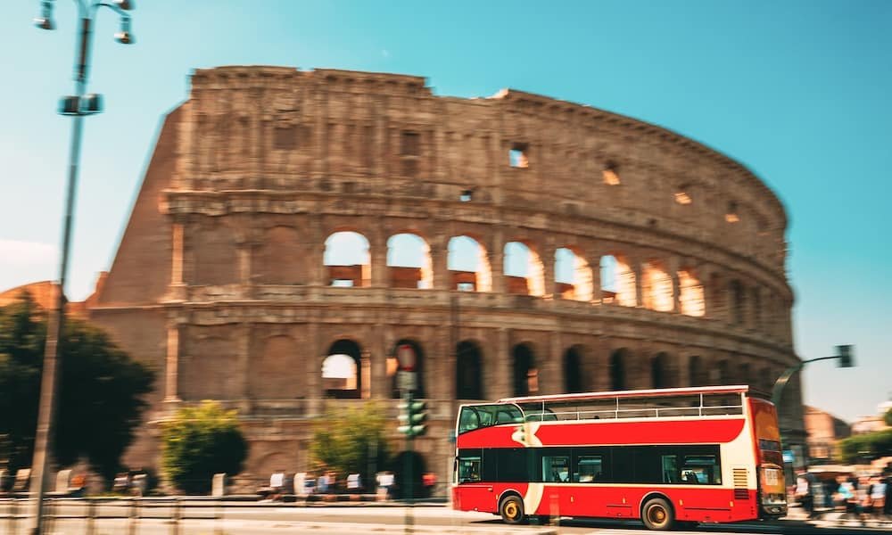 A red double-decker bus in front of the Colosseum